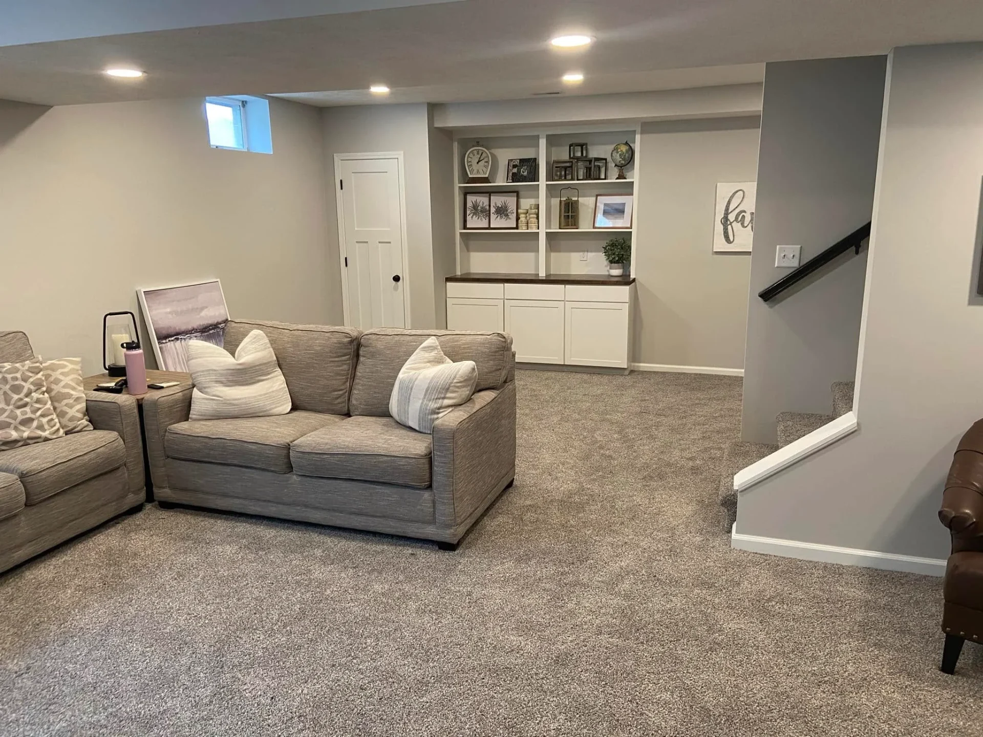 Finished basement living space with LVP flooring and recessed lighting