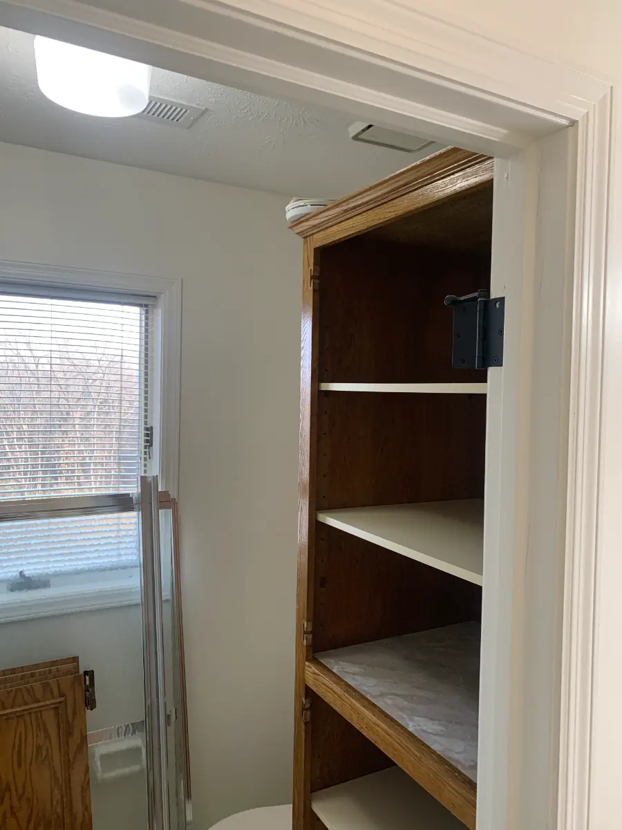 bathroom remodel with custom linen cabinet and floating shelves, before