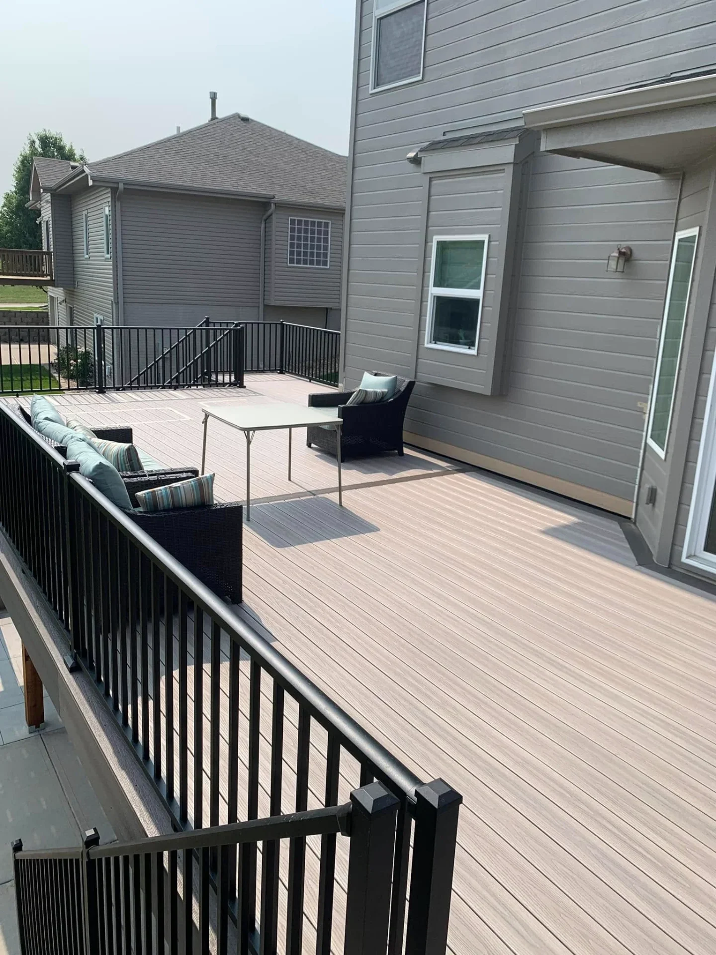 Composite deck attached to the back of a Midwestern home with outdoor furniture